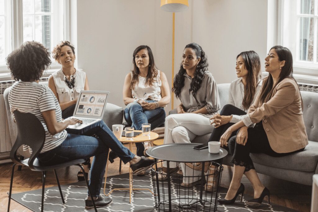 Women participating in a group coaching session discussing business growth and economic empowerment in a collaborative setting